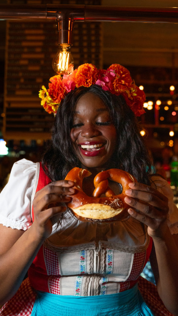 Woman eating pretzel, wearing Bavarian attire for Oktoberfest