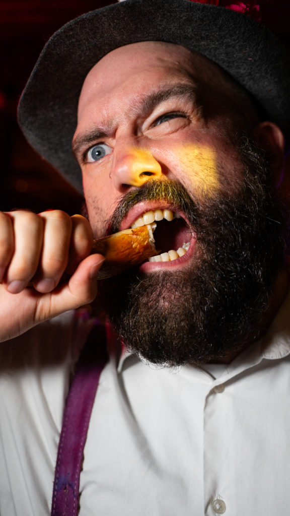 Up-close image of man in Bavarian attire eating a wiener for Oktoberfest